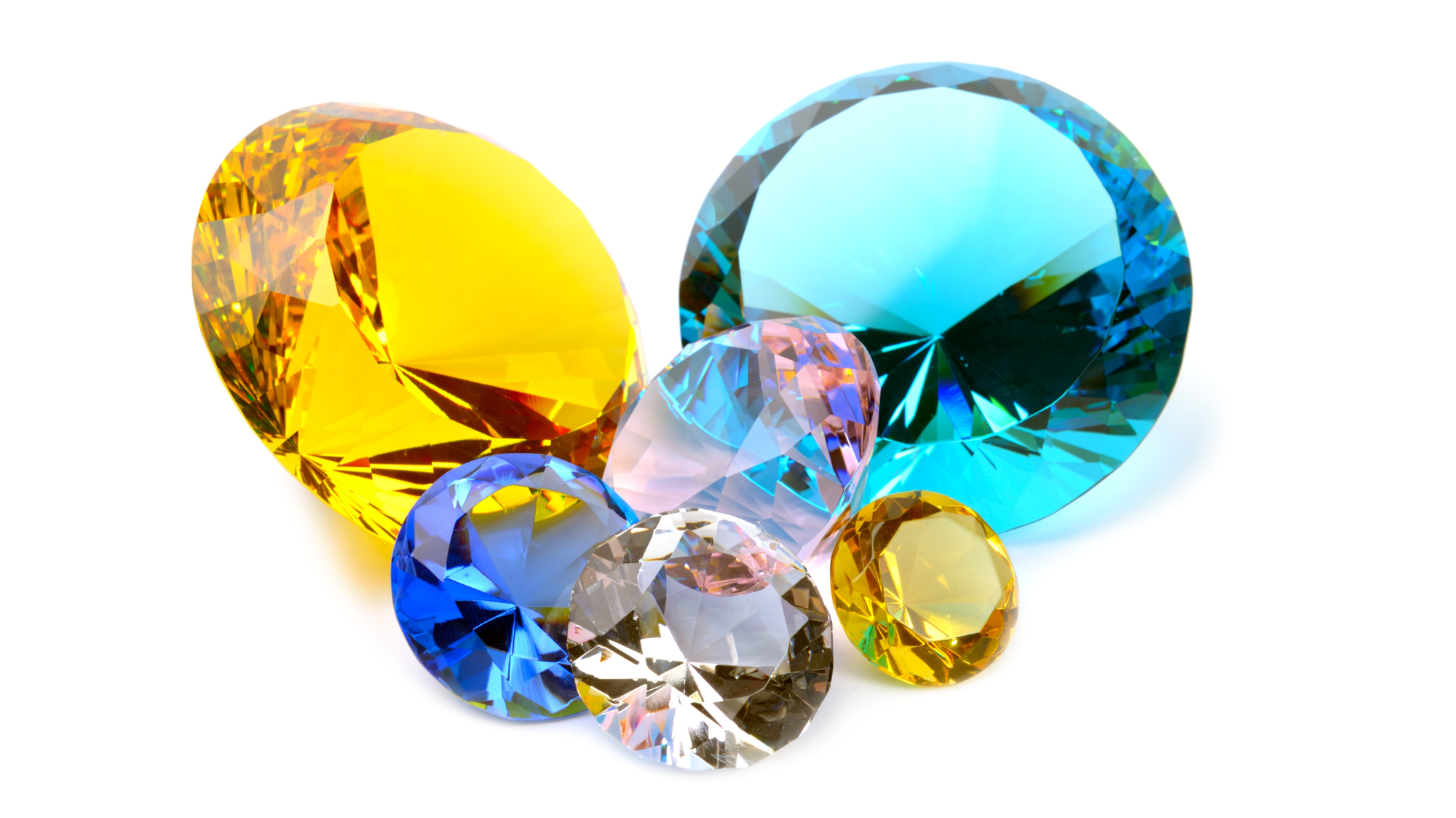 Bunte lose Diamanten, gelb, blau, transparent, facettiert auf weißem Hintergrund